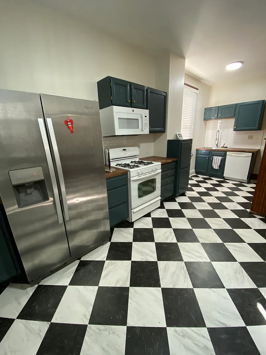 Kitchen with dark teal cabinets, gas range, dishwasher, and checkerboard tile floor